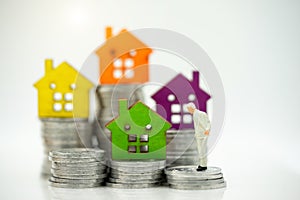 Mainature people standing with coins stack and home.  Home financial investment Concept