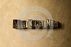 MAINTAINED - close-up of grungy vintage typeset word on metal backdrop