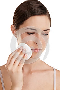 Maintaing her perfect skin. a beautiful young woman exfoliating her face against a white background.