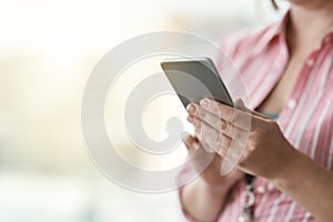 Maintaining her business connections. an unidentifiable businesswoman using a cellphone in an office.