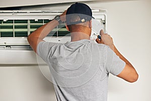 Maintenance, air conditioner and man with screwdriver for problem solving on machine from back. Aircon, ac repair and photo