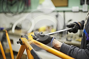 Maintenance of a bicycle: man disassembling an orange bike at his repair shop