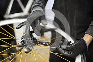Maintenance of a bicycle: man using gloves removing the cassette of a bike wheel