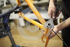 Maintenance of a bicycle: person disassembling an orange bike in his workshop