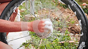 Maintenance bike. Bike mechanic washing bicycle wheel and cassette with soap foam, degreaser and washcloth outdoors. Male technici