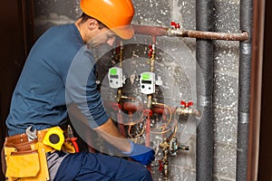 Maintenance engineer checking technical data of heating system equipment in a boiler room. Plumber installing pressure