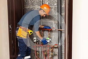 Maintenance engineer checking technical data of heating system equipment in a boiler room. Plumber installing pressure