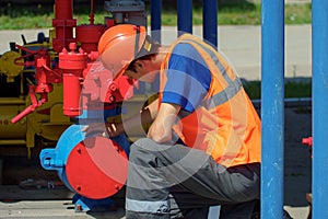 Maintenance of industrial gas equipment. working man in hard hat checks equipment in warehouse on summer day