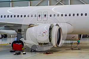 Maintenance Mechanic is Inspecting and Working on Airplane Jet Engine in Hangar photo