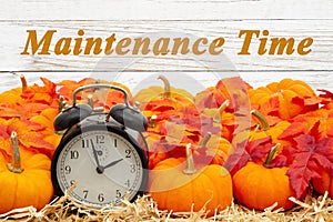 Maintenance Time message with a retro alarm clock with pumpkins and fall leaves