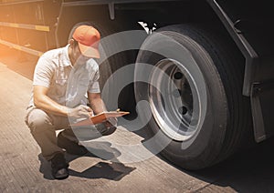 Maintenance and Vehicle inspection. Asian a truck mechanic driver holding clipboard his checking safety a truck wheels and tires.