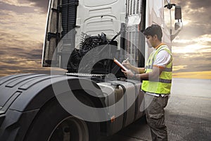 Maintenance and Vehicle inspection. A truck mechanic driver holding clipboard his inspecting safety a large fuel tank of semi truc