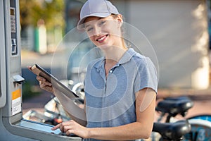 maintenance woman checking parking terminal with tablet photo