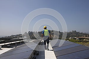 Maintenance Worker Inspecting Solar Panels On Rooftop photo