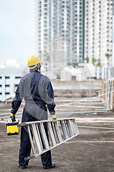 Maintenance worker man carrying aluminium ladder