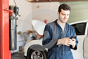 Maintenance Worker Using Mobile Phone In Auto Repair Shop