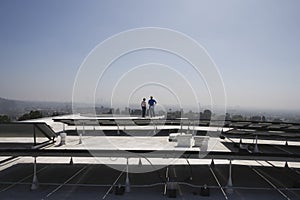 Maintenance Workers Near Solar Panels On Rooftop