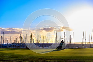 Maintenance works with lawn mower of evergreen grass field on large golf course and yacht club marina on Tenerife island, Canary,
