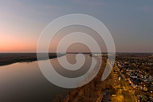 A majestic aerial shot of the flowing waters of the Mississippi river with blue sky at sunset and a view of the homes