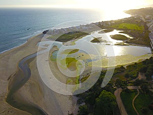 A majestic aerial shot of the lagoon along the mountain ranges with a freeway with cars driving and lush green trees and plants