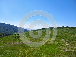 a majestic aerial shot of the lush green hillsides and mountains with a long winding road