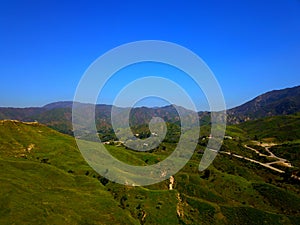 a majestic aerial shot of the lush green hillsides and mountains with a long winding road