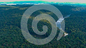 A majestic aerial shot of vast miles of lush green trees with the Chattahoochee river running through them with blue sky and cloud