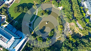 A majestic aerial shot of a water fountain in the middle of a lush green lake surrounded by lush green and autumn colored trees