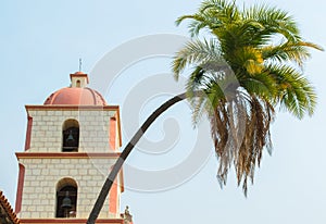 Majestic bending palm tree near a bell tower at the historic Santa Barbara mission