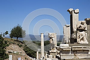 Majestic columns and ruins of the ancient city of Ephesus against the backdrop of tree-covered hills of the blue sky