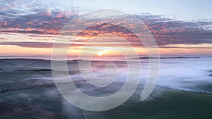 Majestic drone landscape image of sea of fog rolling across South Downs English countryside during Spring sunrise