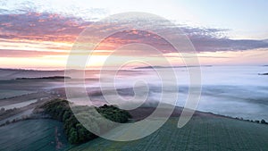 Majestic drone landscape image of sea of fog rolling across South Downs English countryside during Spring sunrise