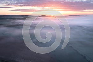 Majestic drone landscape image of sea of fog rolling across South Downs English countryside during Spring sunrise