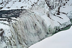 Majestic frozen waterfall with icy cliffs and snow-covered rocks, showcasing nature's winter beauty.