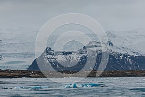 majestic icelandic landscape with snow-covered rocky mountains and icebergs in water,
