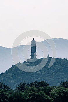 Majestic ivory-hued tower stands atop a rolling green hill dotted with lush trees.