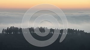 Majestic landscape image of cloud inversion at sunset over Dartmoor National Park in Engand with cloud rolling through forest on
