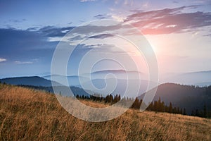 Majestic landscape of mountains at sunrise. View of the misty tops and layer hills of the mountains in the distance.