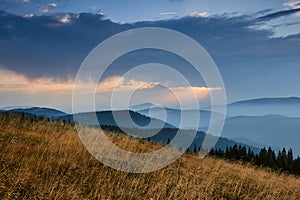 Majestic landscape of mountains at sunrise. View of the misty tops and layer hills of the mountains in the distance.