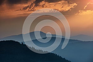 Majestic landscape of mountains at sunrise. View of the misty tops and layer hills of the mountains in the distance.