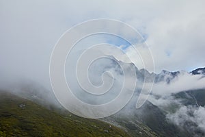 Majestic landscape of summer mountains. View of rocky peaks and coniferous forest hills in fog. Fagaras Mountains. Romania.