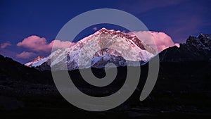 Majestic mountain Nuptse surrounded by clouds in the purple evening light viewed from small village Lobuche, Nepal.