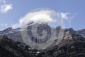 a majestic mountain peak with snow under a blue sky, accented by white clouds in ordesa