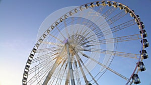 Majestic observation wheel rotating in amusement park, sunny blue sky background