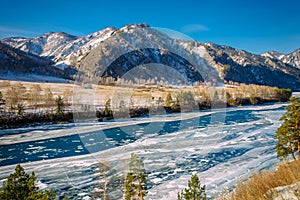 Majestic panoramic view of the valley covered with snow, turquoise river on the background of snow-capped mountains and clear blue