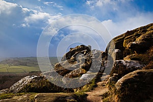 Majestic rocky landscape with sunlit grass under a blue sky with clouds at Brimham Rocks, in North Yorkshire