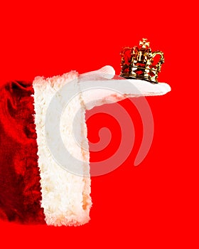 Majestic royal celebrations of Christmas. Santa`s hand in a white glove holds a golden crown, a gift for Christmas. Can be used a