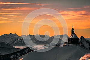 Majestic scene of a traditional alpine church surrounded by snow-covered mountains in Austria
