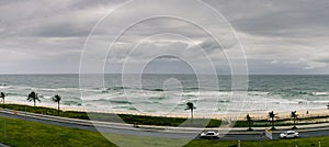 Majestic Seascape of beach, waves, cars, clouds and cyclist on a cloudy day