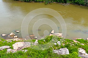 A majestic shot of the silky brown waters of the Chattahoochee river with lush green trees and rocks along the banks of the river